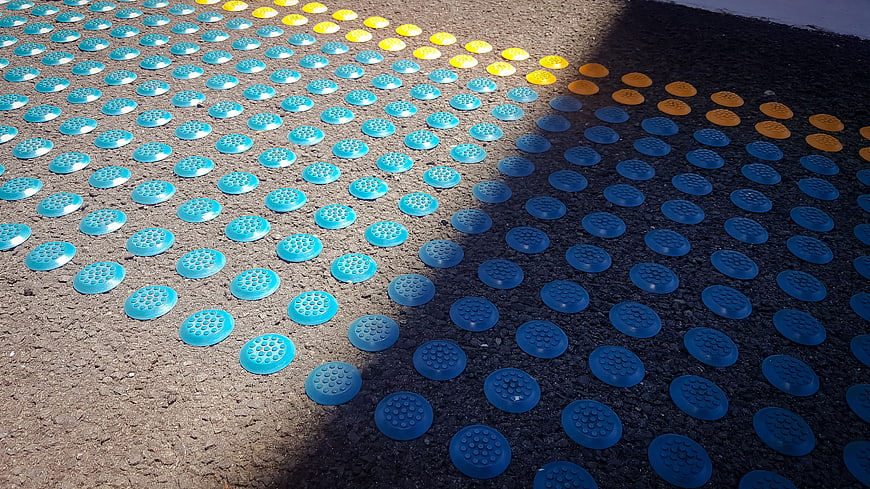 Colorful tactile paving stones on asphalt road surface