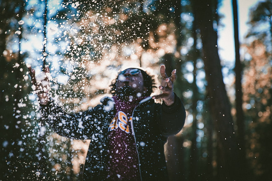 Man throwing snow in forest with sunglasses