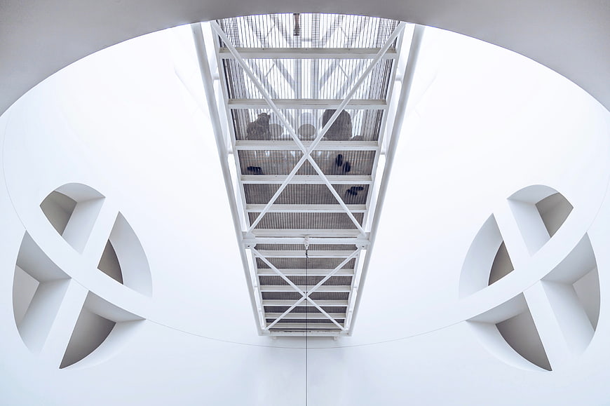 Symmetrical white architectural interior with geometric ceiling details