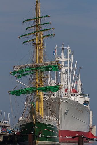 Historic sailing ships docked at a harbor