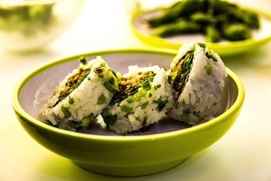 Japanese onigiri rice balls with green onions in a bowl