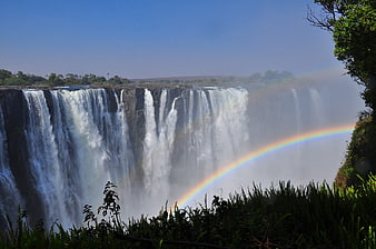 Victoria Falls Waterfall With Rainbow And Lush Green Vegetation