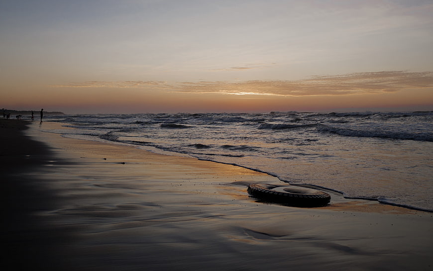 Sunset Beach Scene with Tire on Wet Sand