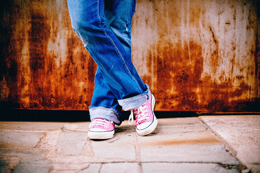 Pink Sneakers and Blue Jeans Against Rusty Wall