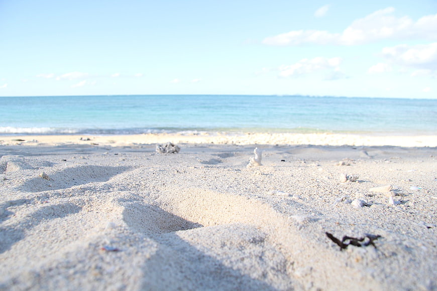 Sandy Beach Shoreline With Turquoise Ocean And Blue Sky