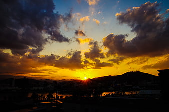 Dramatic sunset over city skyline with golden clouds