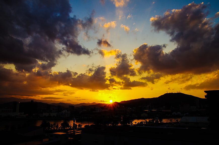 Dramatic sunset over city skyline with golden clouds