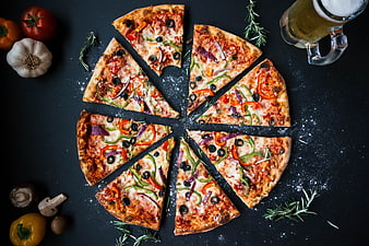 Flat lay of sliced vegetable pizza with beer and ingredients