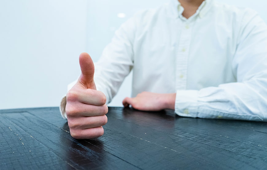 Businessman giving thumbs up gesture on dark wooden table