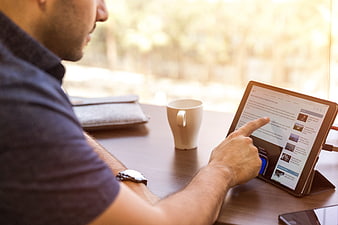 Man using tablet computer at desk with coffee
