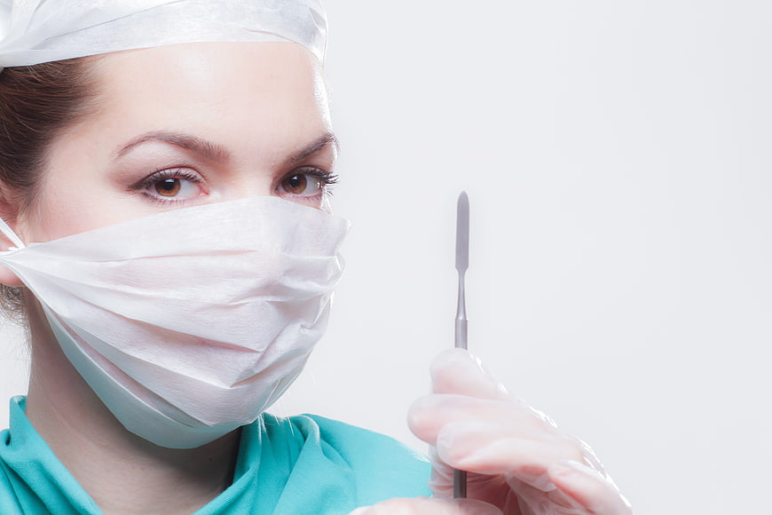 Female Surgeon Holding Scalpel in Medical Scrubs