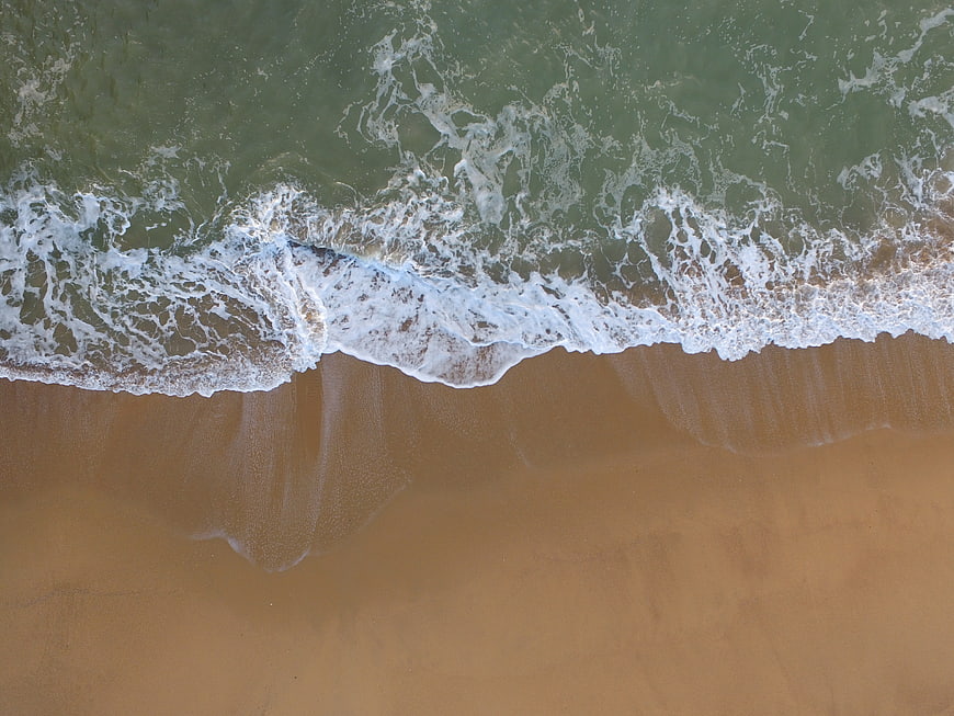 Aerial View of Ocean Waves Crashing on Sandy Beach