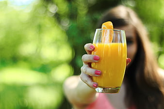 Woman Holding Fresh Orange Juice in a Glass Outdoors