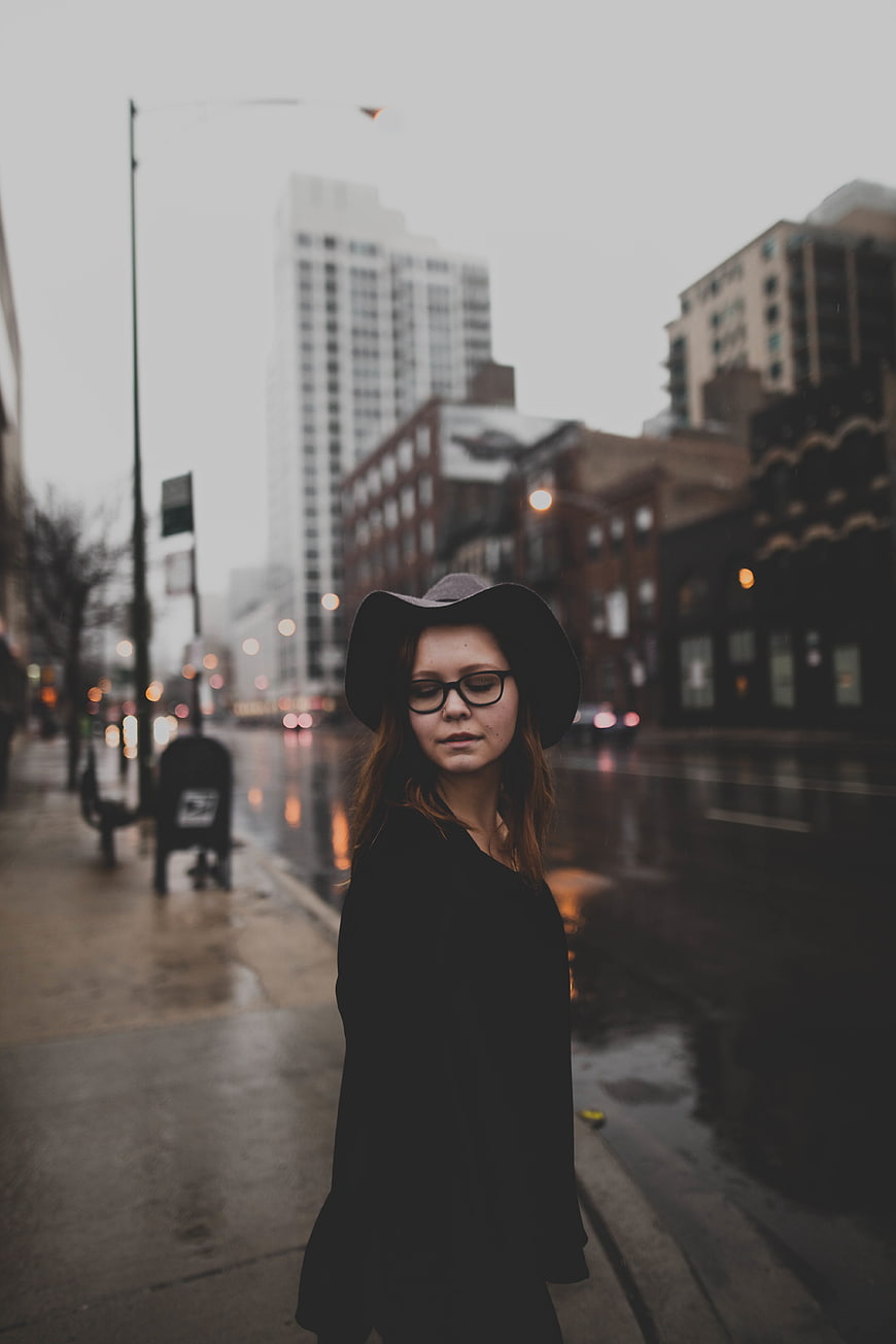 Woman in Hat and Glasses on Rainy City Street