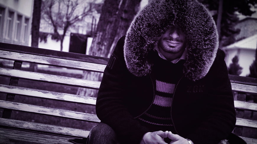 Man in Fur Hat Sitting on Park Bench in Winter