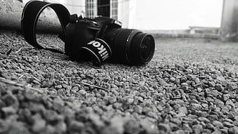 Black and White Nikon Camera on Gravel Ground
