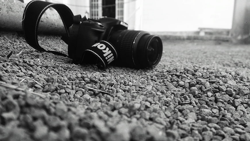 Black and White Nikon Camera on Gravel Ground