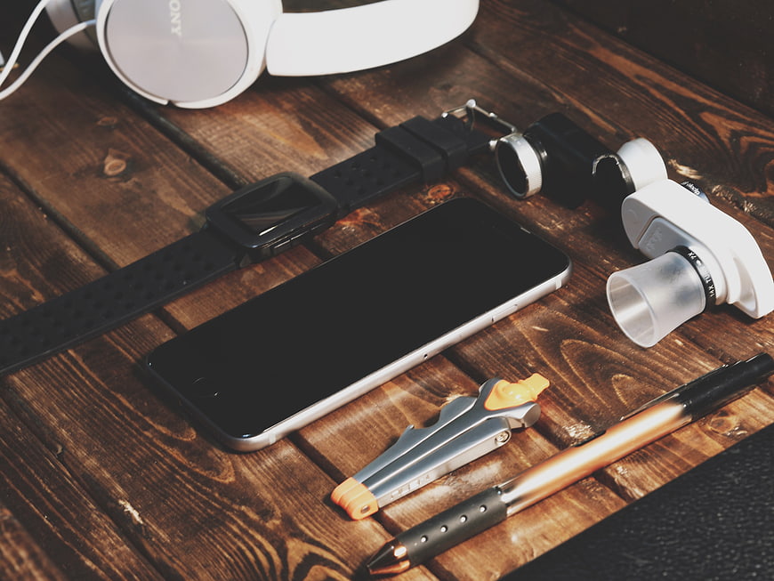Flat lay of smartphone, headphones, and accessories on wood