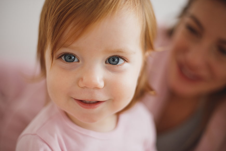 Close-up portrait of smiling toddler girl with blue eyes