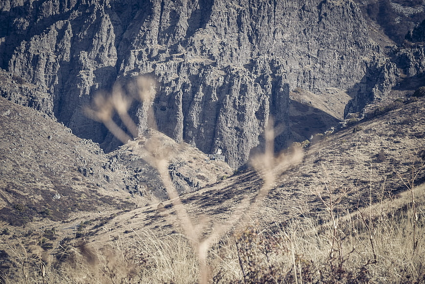 Rugged mountain landscape with dry grass foreground and rocky cliffs