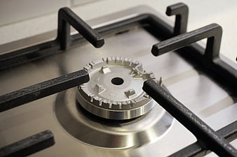 Close-up of a stainless steel gas stove burner with black grate