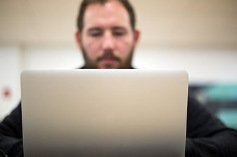Man working on laptop in office with blurred background