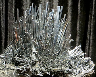Close-up of silvery metallic mineral crystals on dark background
