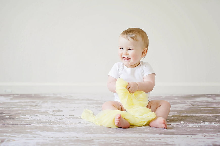 Happy Baby Sitting on Floor with Yellow Fabric