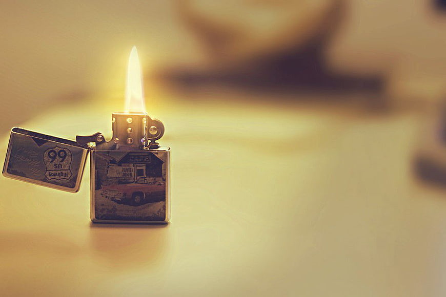 Vintage Zippo lighter with flame on wooden table