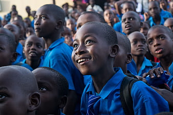 Smiling African schoolboy in blue uniform surrounded by classmates