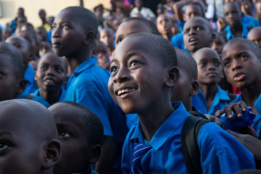 Smiling African schoolboy in blue uniform surrounded by classmates