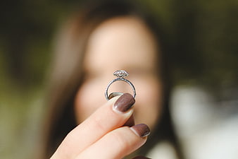 Woman holding diamond engagement ring with blurred background