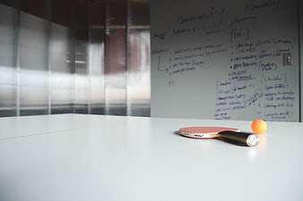 Ping Pong Paddle and Ball on White Table with Whiteboard
