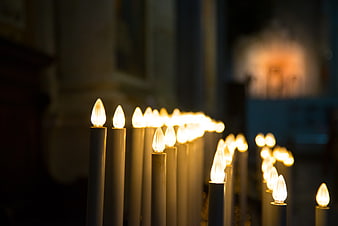 Rows of lit prayer candles in a dimly lit church interior