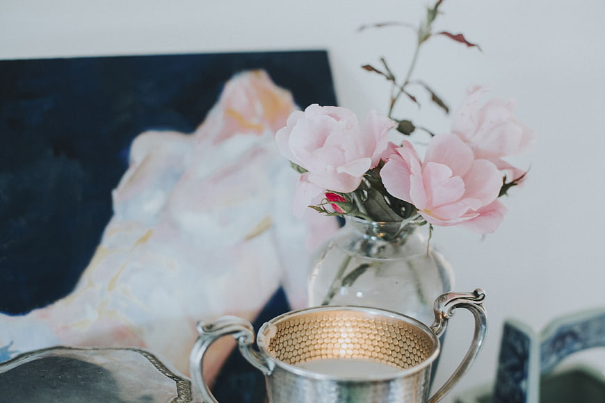 Pink peonies in glass vase with silver cup and abstract art