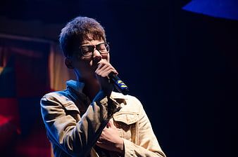Young Asian man singing passionately into microphone on stage