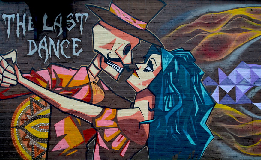 Colorful street art mural of skeleton and woman dancing