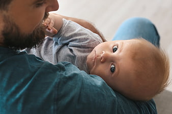 Father holding newborn baby looking at camera