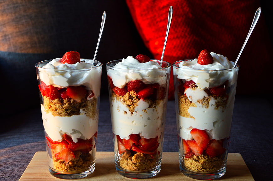 Three Strawberry Parfaits with Cream and Biscuit Crumbs