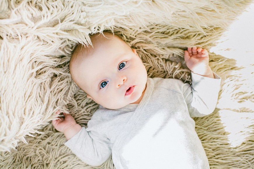 Cute newborn baby lying on fluffy beige rug