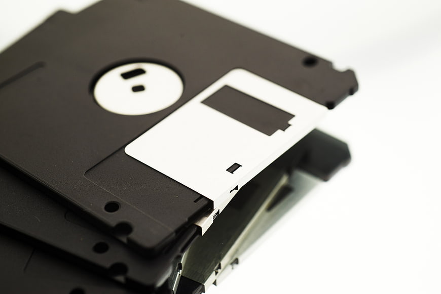 Stack of black 3.5-inch floppy disks on white background