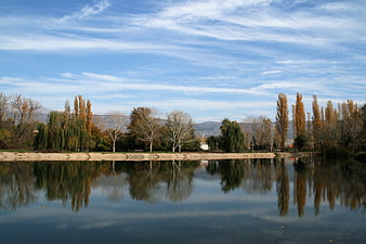 Serene autumn river landscape with tree reflections and blue sky
