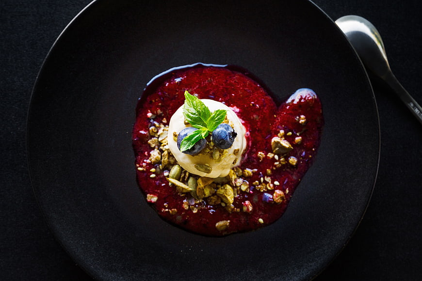 Overhead view of gourmet dessert with berry sauce and granola