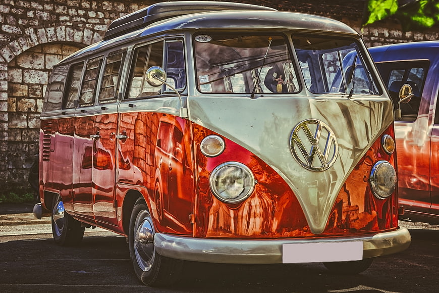 Classic Red and Silver VW Camper Van Parked Against Stone Wall