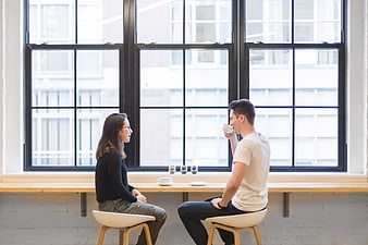 Couple having coffee conversation by large window