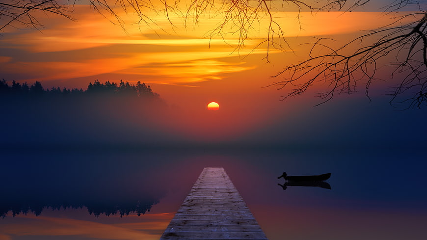 Serene Sunset Over Misty Lake with Wooden Pier and Boat