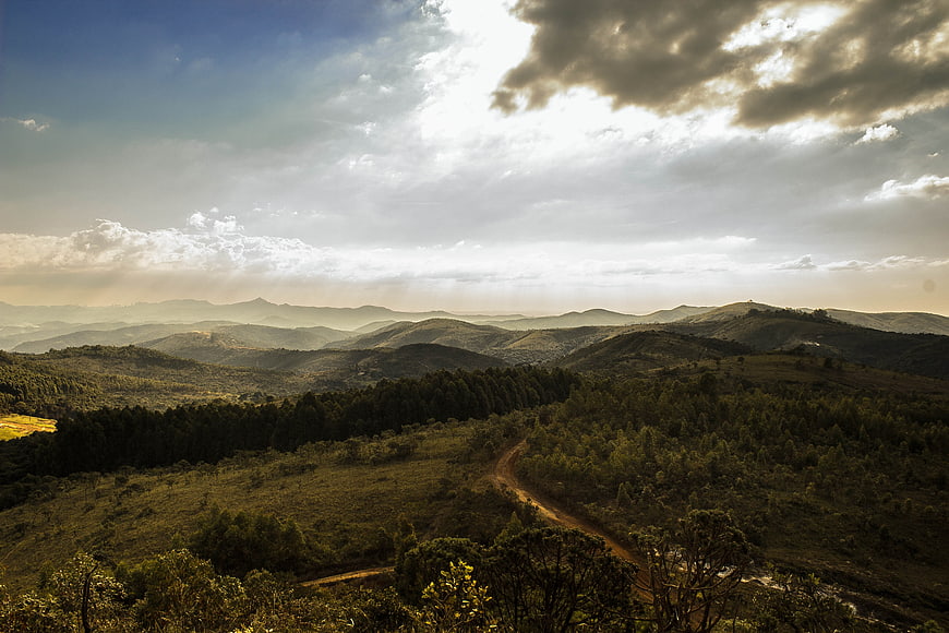 Scenic mountain landscape with winding dirt road and dramatic clouds