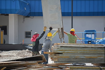 Construction workers lifting concrete panel at building site