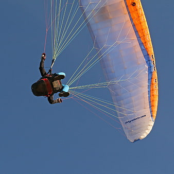 Paraglider flying against clear blue sky