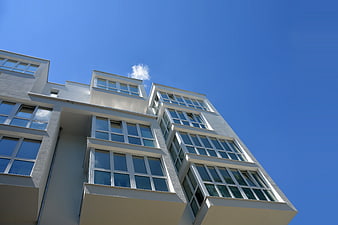 Low angle view of modern white apartment building against blue sky